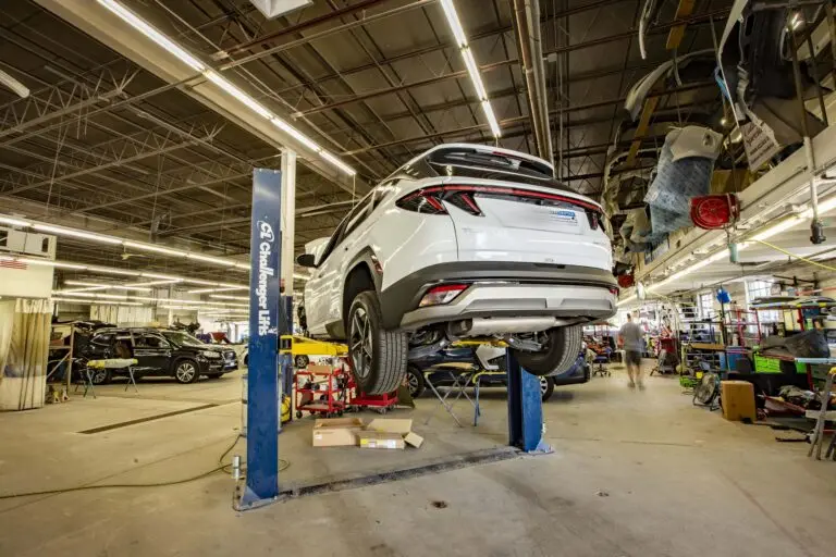 Collision Center 1 auto body repair facility in Golden Valley, MN, with a white SUV raised on a vehicle lift.