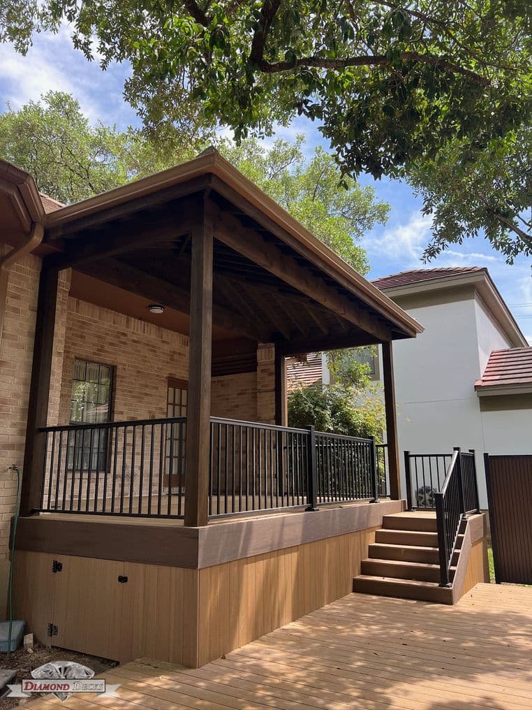 Covered porch with wood patio cover and black metal railings by Diamond Decks, San Antonio, TX