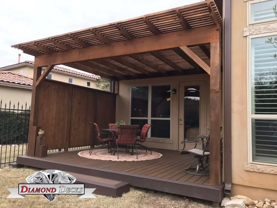 Stained cedar pergola with privacy wall over composite deck by Diamond Decks, San Antonio TX