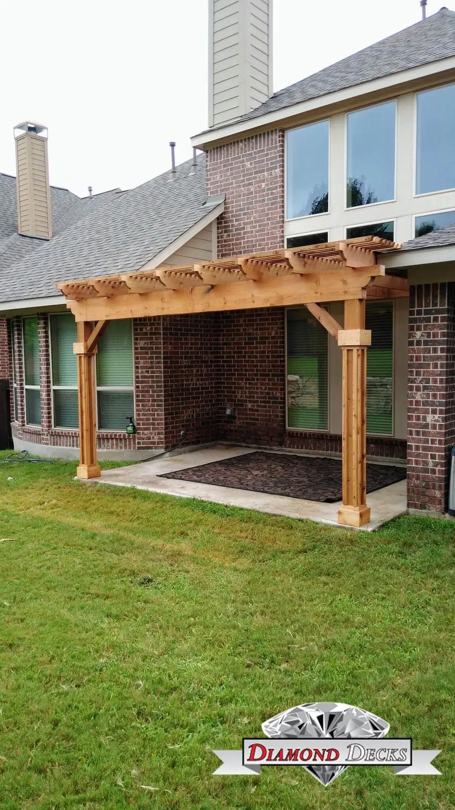 Attached cedar pergola with wrapped posts on a brick home by Diamond Decks, San Antonio TX