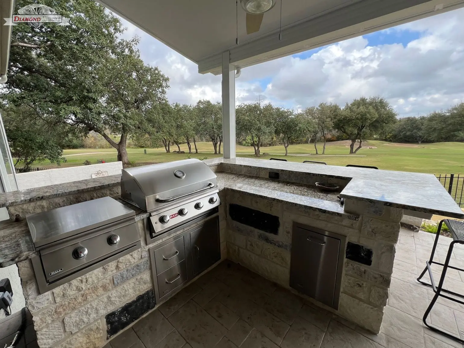 Covered patio outdoor kitchen with Bull grill and granite bar overlooking a golf course, built by Diamond Decks in San Antonio, TX