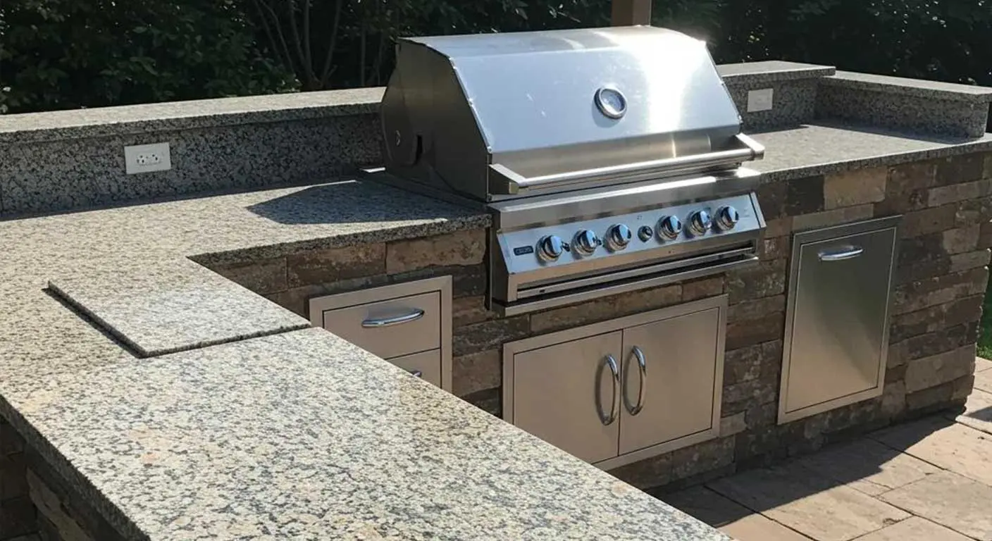 Outdoor kitchen island with stone base and stainless grill under a patio cover in San Antonio, TX