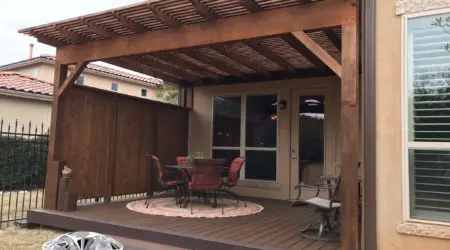 Stained cedar pergola with privacy wall over composite deck by Diamond Decks, San Antonio TX
