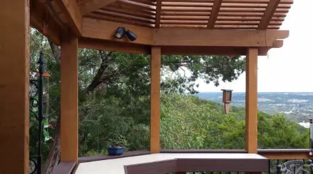 Cedar pergola with angled corner rafters over elevated composite deck by Diamond Decks, San Antonio TX