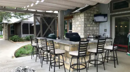 Shade sail patio cover over stone bar with swivel stools by Diamond Decks, San Antonio TX