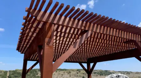 Underside of stained pergola with dense rafters against hill views by Diamond Decks, San Antonio TX
