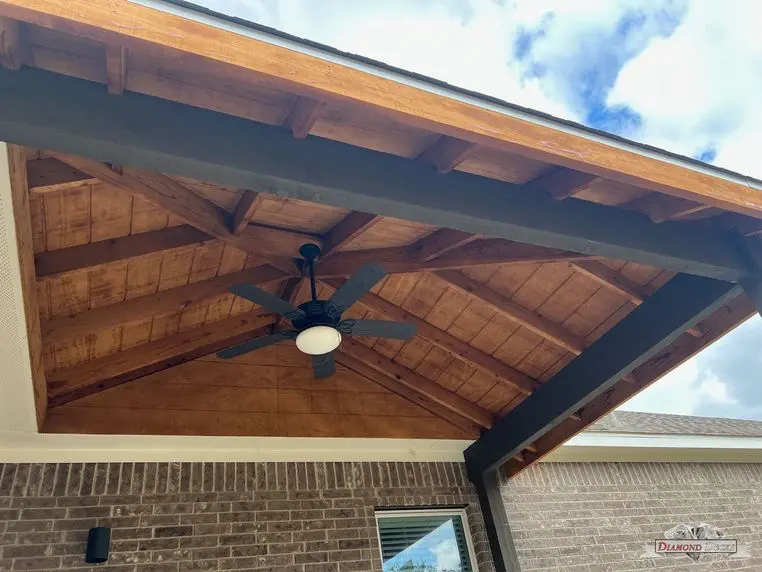 Stained wood ceiling and ceiling fan under a gable patio cover built by Diamond Decks
