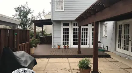 Dark-stained pergola over composite deck with French doors by Diamond Decks, San Antonio TX