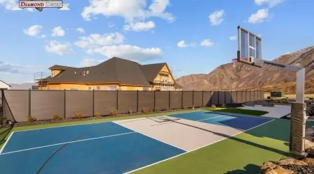 Gray composite privacy fence around a backyard sport court by Diamond Decks, San Antonio, TX