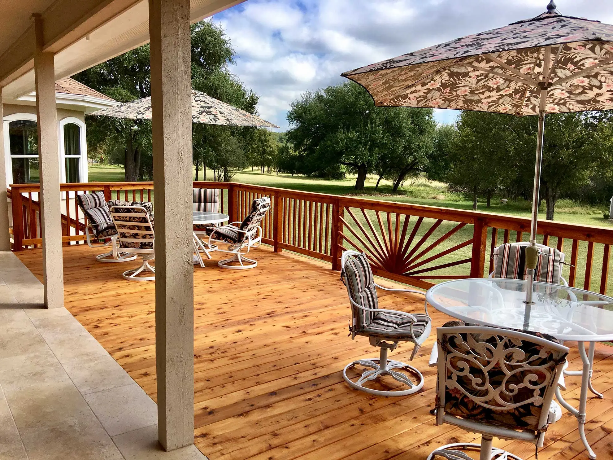 Covered cedar deck with sunburst railing overlooking a Texas ranch by Diamond Decks