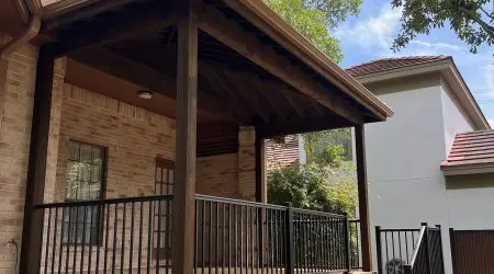 Covered porch with wood patio cover and black metal railings by Diamond Decks, San Antonio, TX