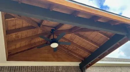 Stained wood ceiling and ceiling fan under a gable patio cover built by Diamond Decks