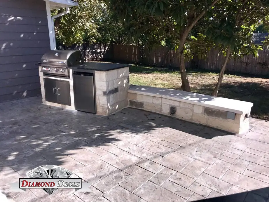 Small limestone grill island with refrigerator and seat wall by Diamond Decks in San Antonio, TX