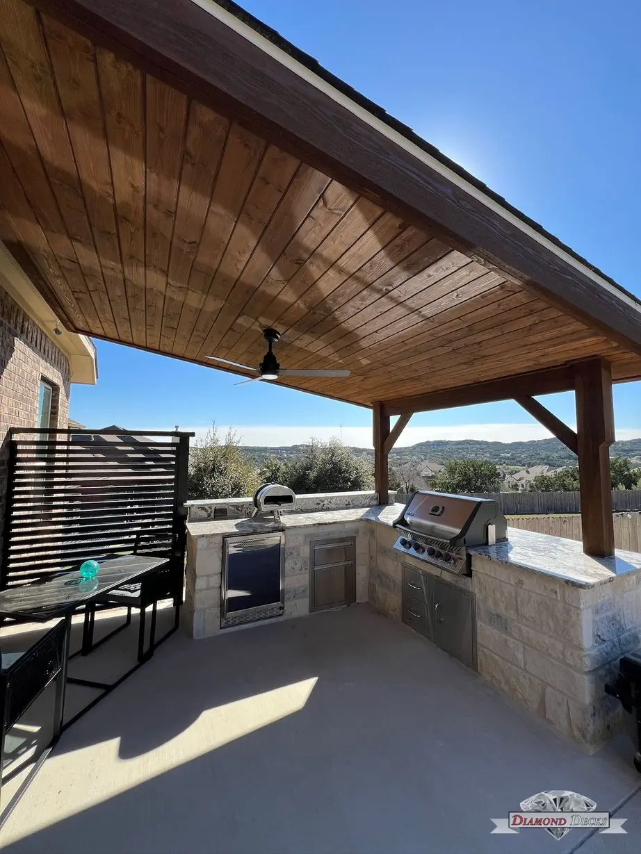 Stained patio cover over limestone kitchen with pizza oven by Diamond Decks in San Antonio, TX