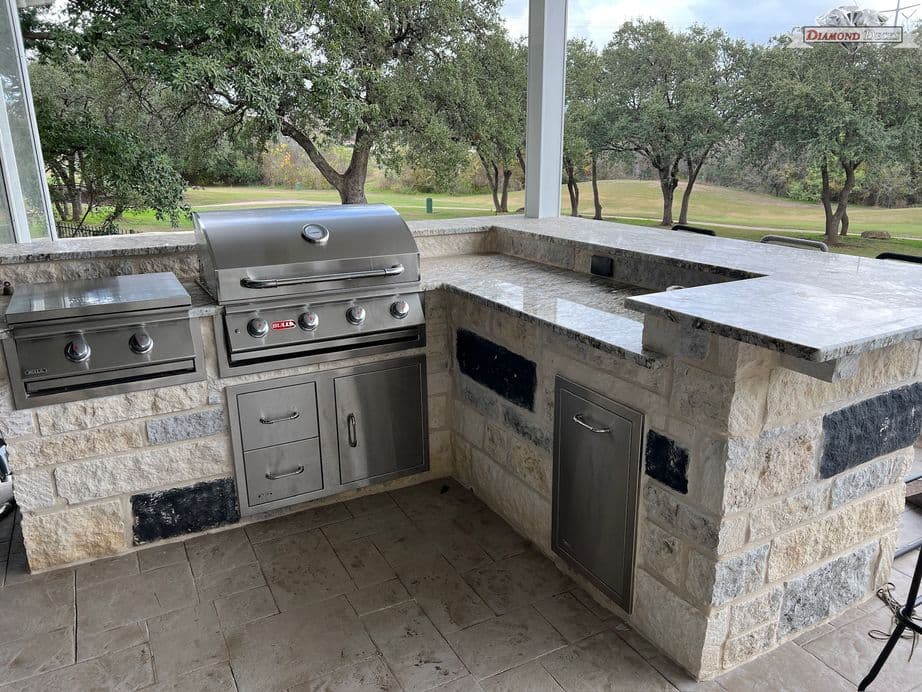 White limestone kitchen with granite counters and raised bar by Diamond Decks in San Antonio, TX