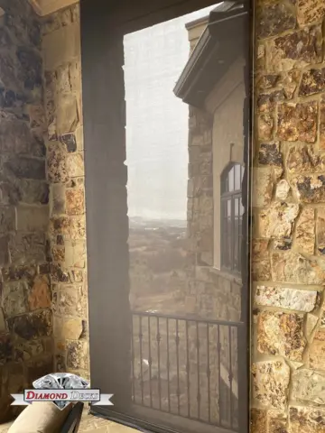 Retractable screen shade enclosing a stone patio doorway