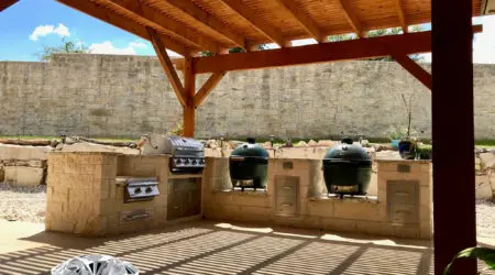 Underside of cedar pergola shading limestone grill and smoker kitchen by Diamond Decks, San Antonio TX