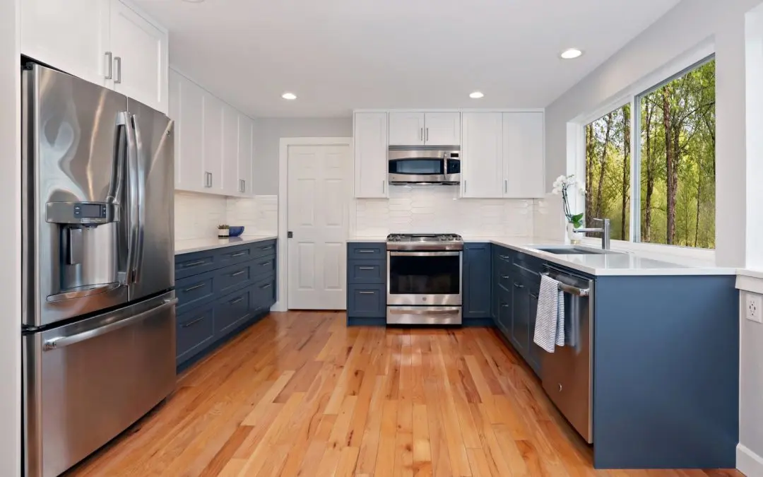 Two tone kitchen with white uppers, navy lower cabinets, picket tile backsplash and stainless appliances