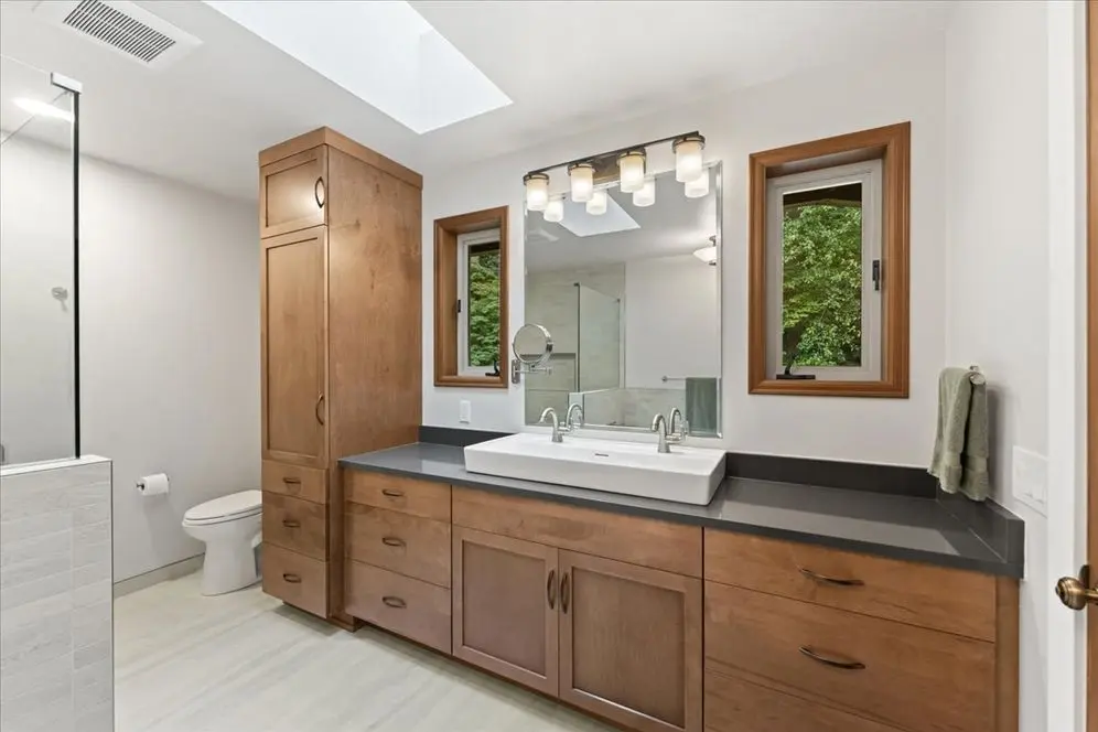 Woodinville bathroom remodel with warm wood vanity, trough sink, freestanding tub and walk-in tile shower