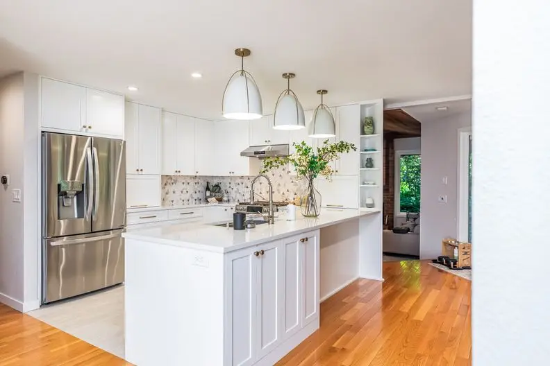 White kitchen with island and brass pendants inside the Zhang remodel and addition White kitchen with island and brass pendants inside the Zhang remodel and addition