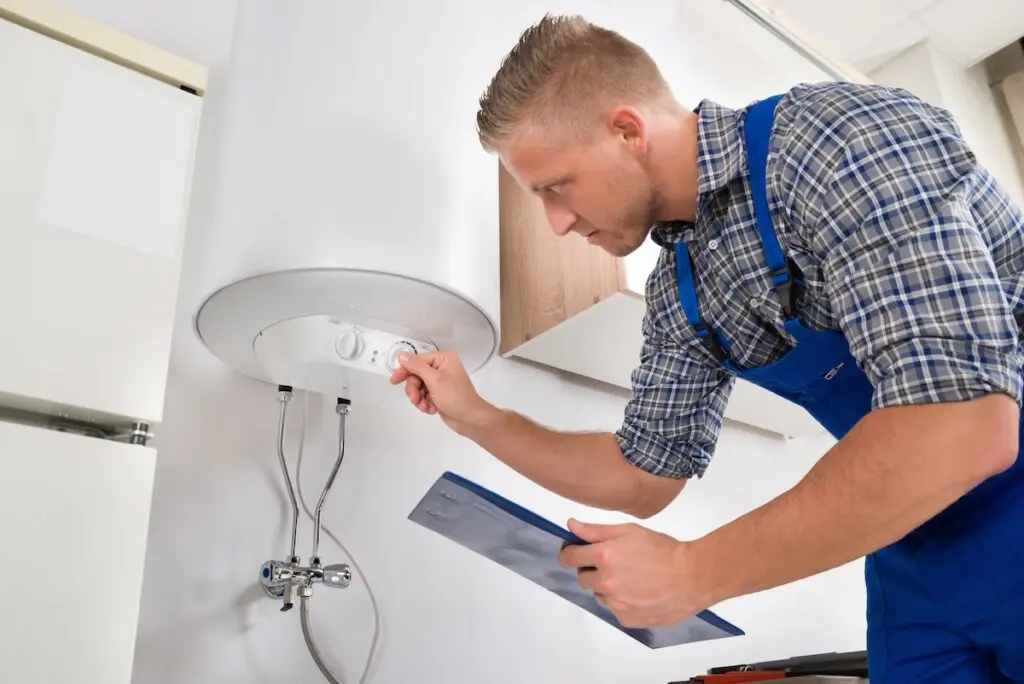 best water heaters Male Worker With Clipboard Adjusting Temperature Of Water Heater