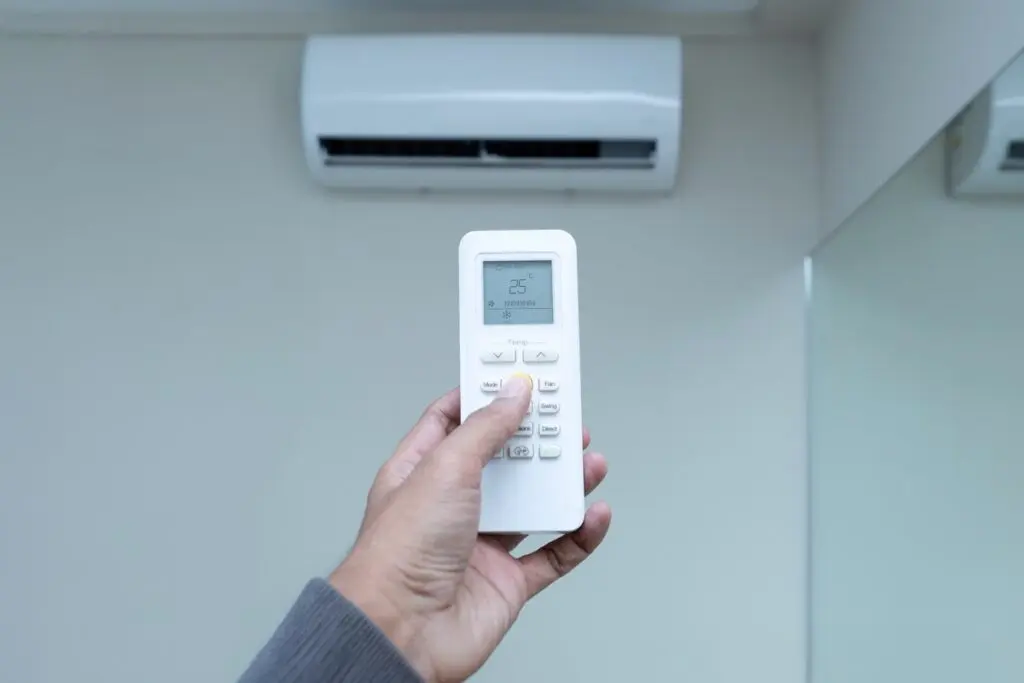A hand holds an air conditioner remote control,