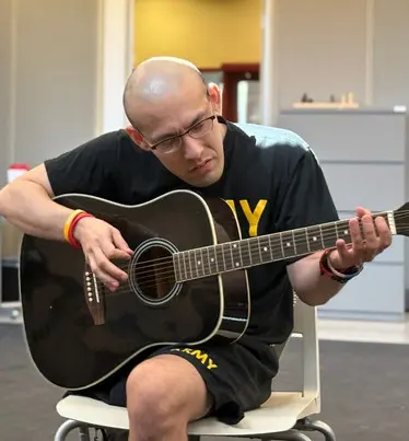 Recovering military personnel practicing guitar.