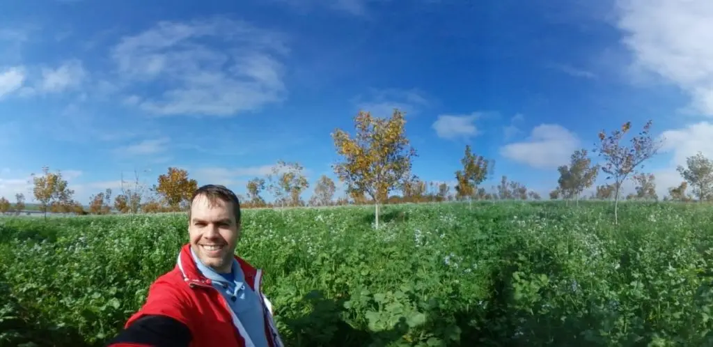 A pecan grower in Brazil takes a selfie in front of his trees.