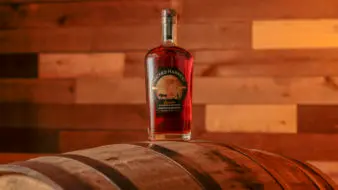 A bottle of Wicked Harvest Pecan Bourbon Whiskey sits on a barrel.