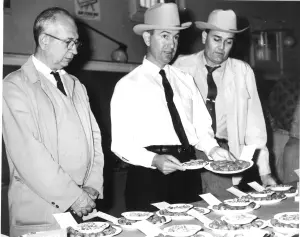 Three men look at and judge inshell pecan entries in one of the first Texas Pecan Show