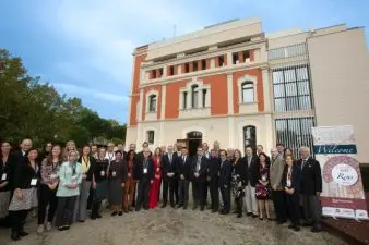 A group of people stand together for a photo outside next to a banner for the NUTS 2022 meeting.