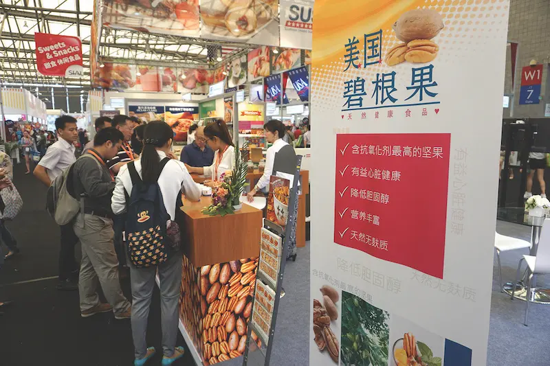 Food show guests crowd around the U.S. Pecans’ booth, where a chef made pecan cookies in line with Chinese tastes and preferences. A sign next to the booth promotes pecans in Chinese.