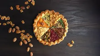 The ThanksEverything Pie sits on a table with some pecan halves scattered around it.