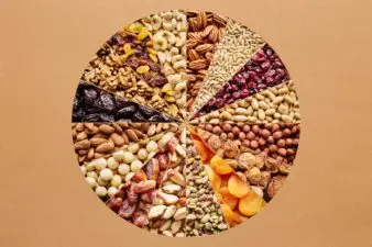 Slices of dried fruit and tree nuts form a circle on a tan background.