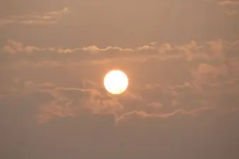A yellow sun burns in a dusky sky.