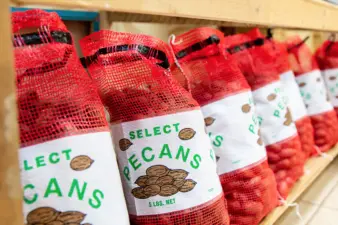 Bagged pecans sit in a line on the bottom of a wooden shelf. The new pecan research and promotion program has the authority to collect assessments for domestic and foreign grown pecans imported into the U.S. USDA announced the industry members on the new APPB