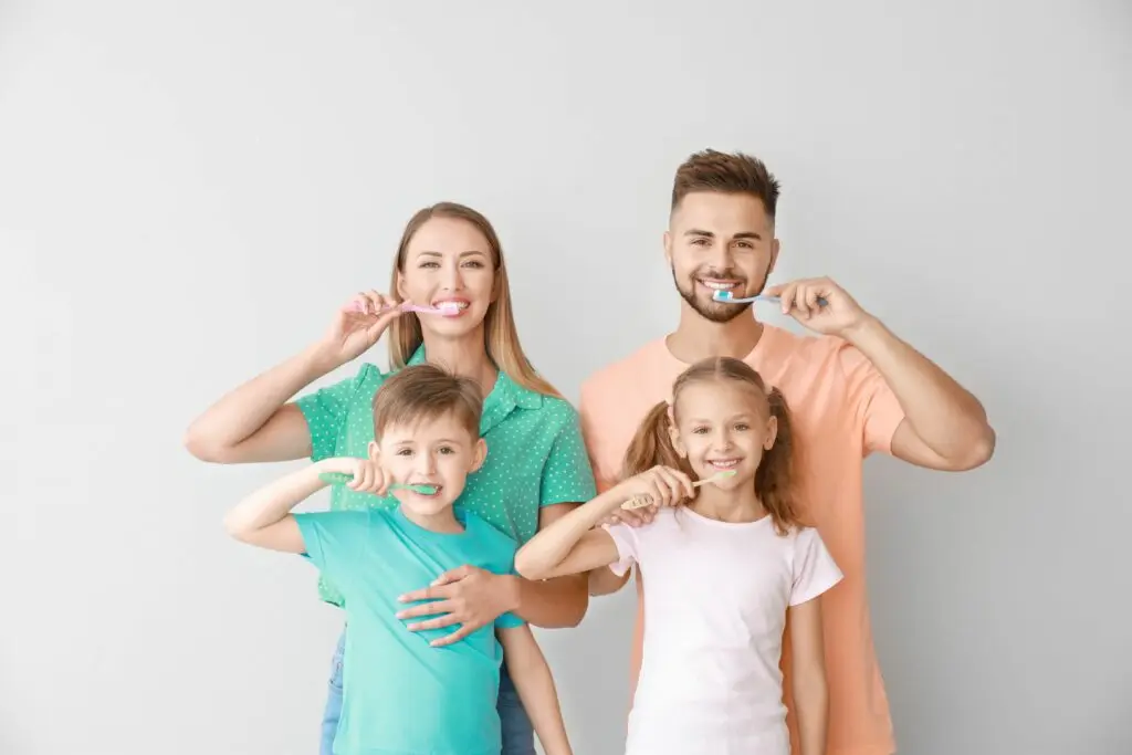 A family with 2 kids performing their routine dental cleanings for healthy, strong teeth.