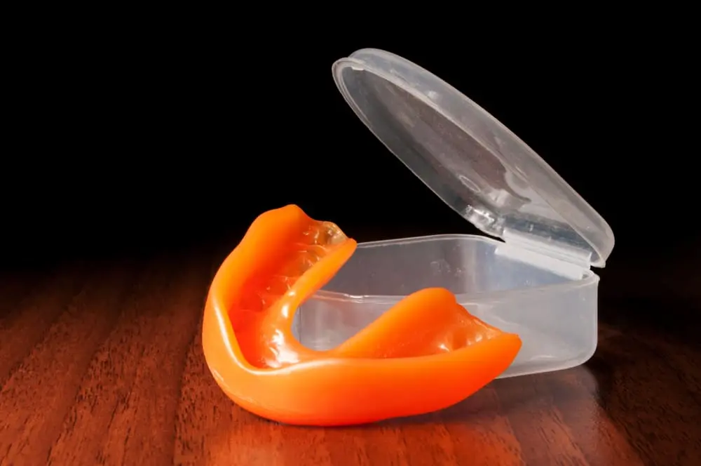 Image of an orange mouthguard, needed to protect the mouth from bruxism or teeth grinding