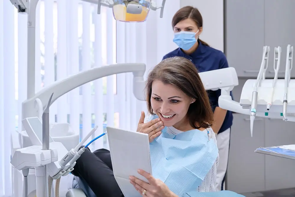 Woman at the cosmetic dentist in Brownsville, looking at her transformed smile after cosmetic dentistry