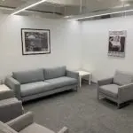 Client Lounge Client lounge with gray couches and chairs at Esquire Deposition Solutions New York City office