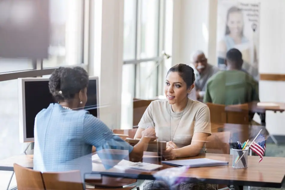 African American banker and Hispanic soldier confer The mature adult African American bank officer helps the Hispanic mid adult female soldier understand the terminology in the loan application form.