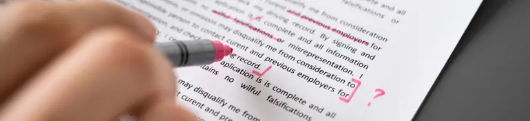 Person editing essay content with red ink