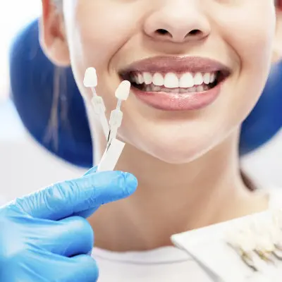 Patient smiling as dentist matches veneer shade for cosmetic dentistry treatment