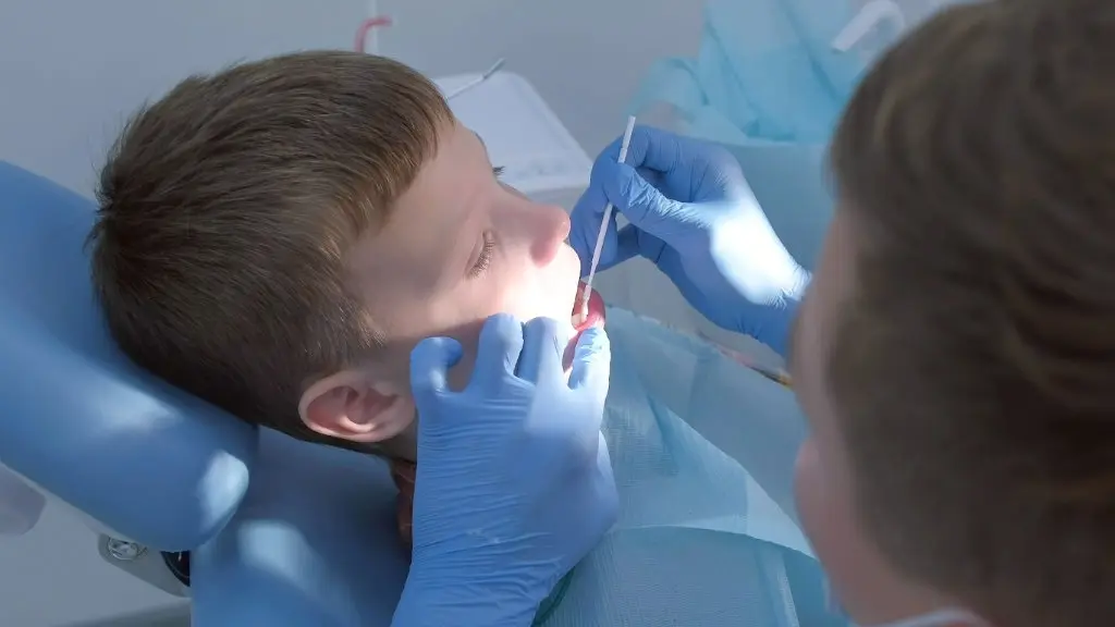 Young boy receiving fluoride treatment in dental chair
