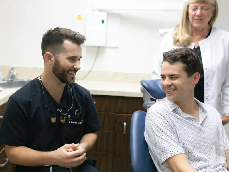 Dr. Jaden Danos consulting with male patient as dental hygienist stands nearby at Danos Dental in Murfreesboro, TN