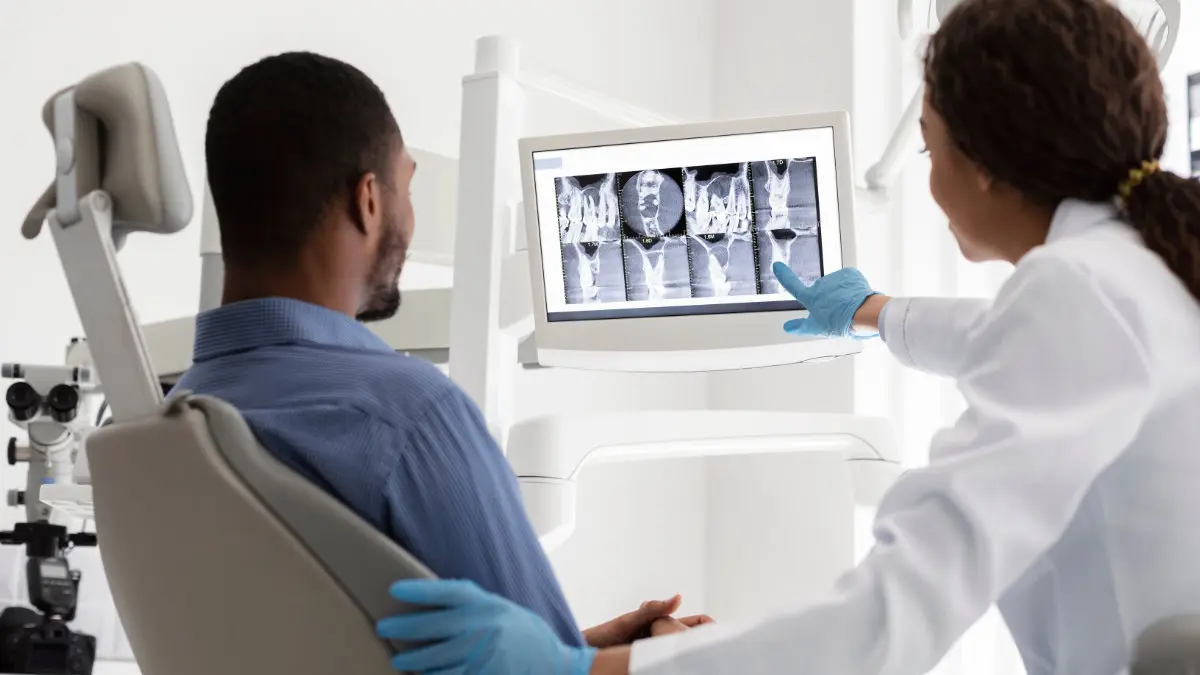 Dentist explaining X-rays to patient during bone grafting consultation