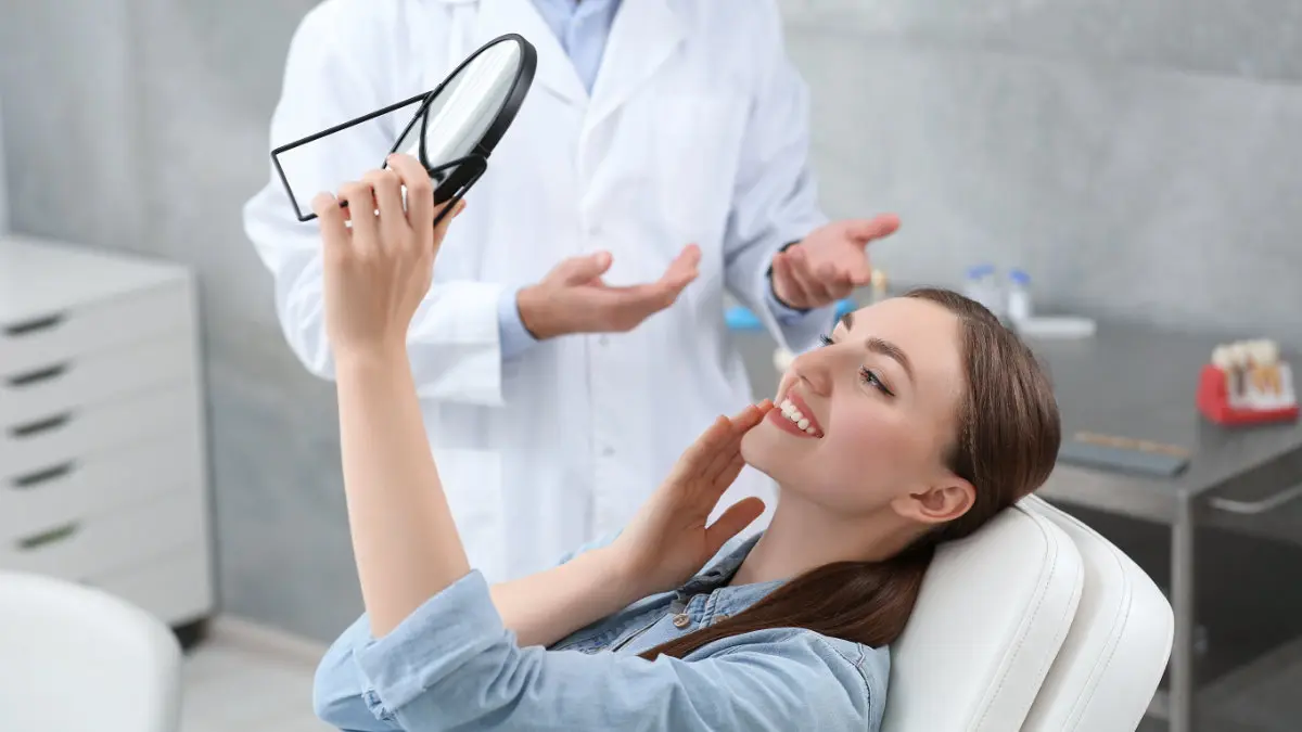 Woman in dental chair looking at her smile during routine dental checkup