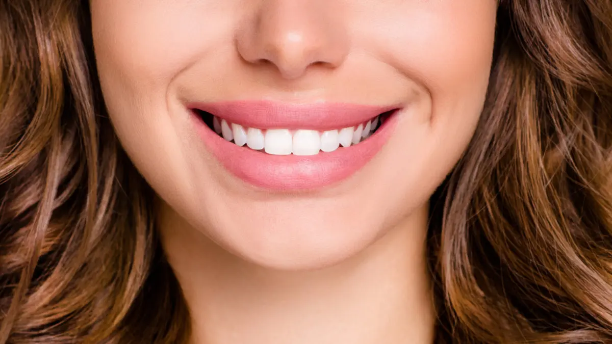 Close-up of woman smiling, showing straight teeth after orthodontic treatment