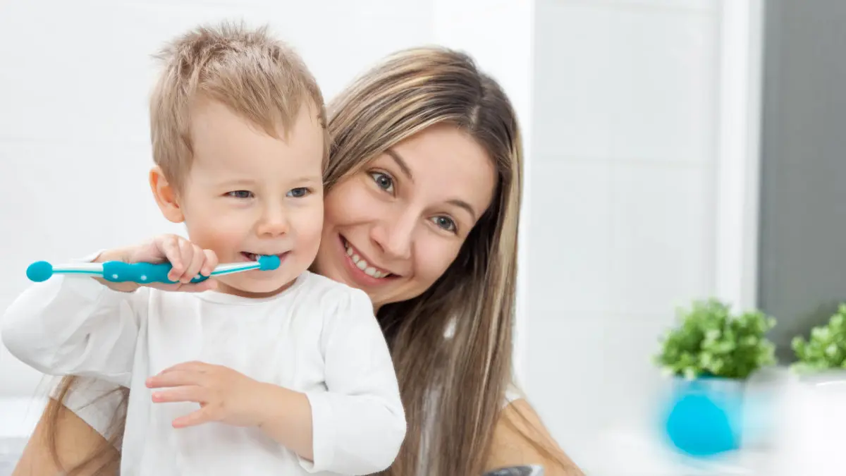 Happy mother teaching her son how to bush his teeth
