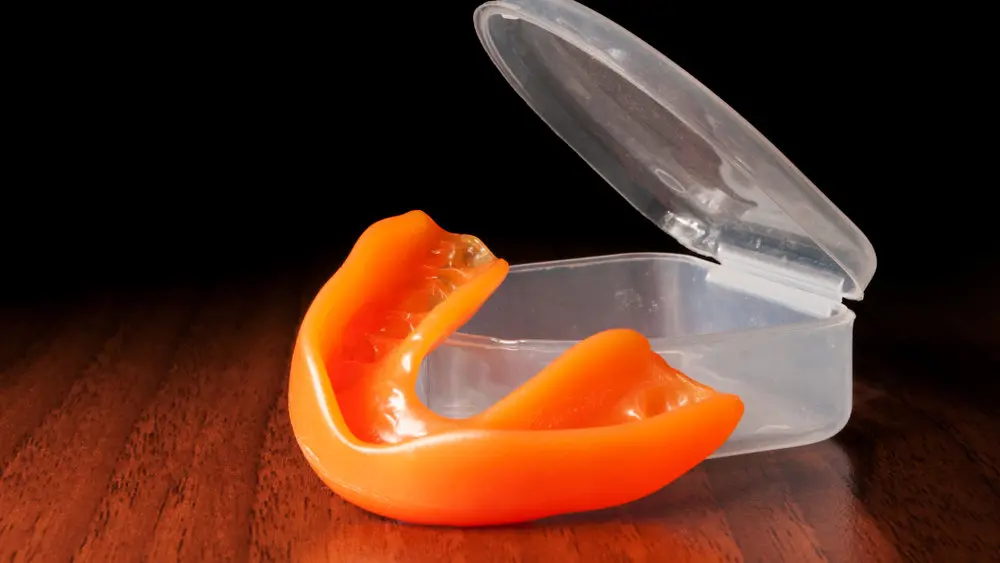 Close-up of orange mouthguard near opened case